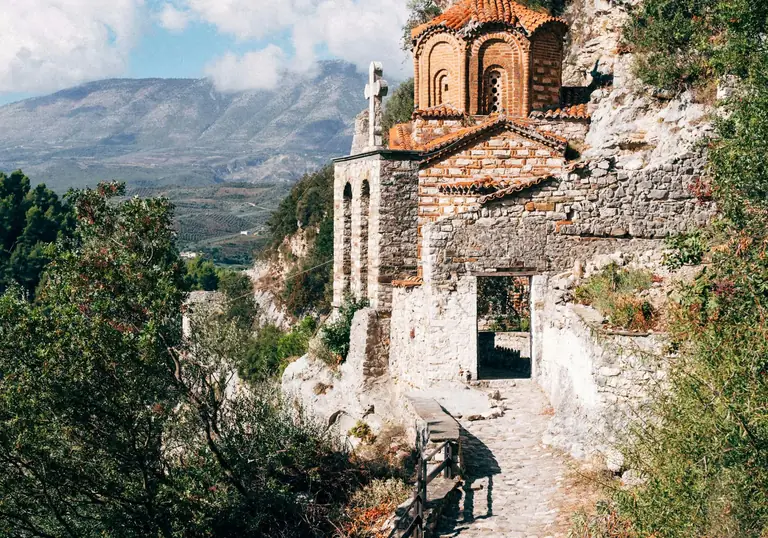 A warm pilgrimage landscape with a winding path, chapel and distant hills.
